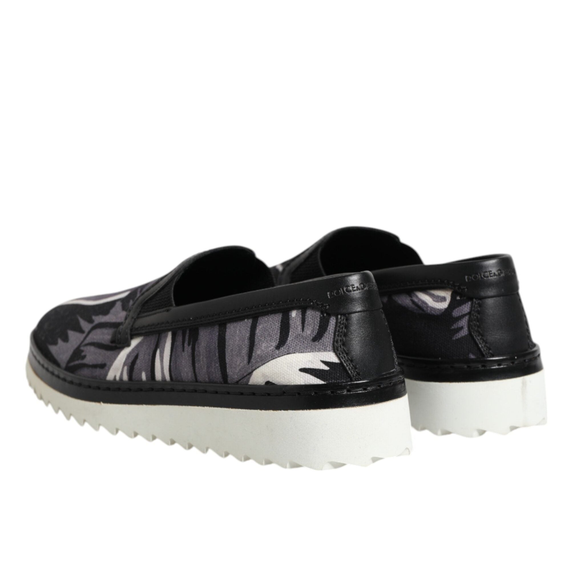 Black slip-on shoes with white soles on a white background