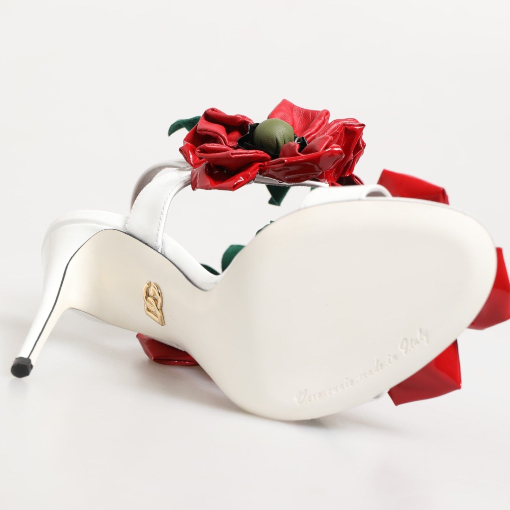 White high-heeled shoes with red floral decorations on a white background