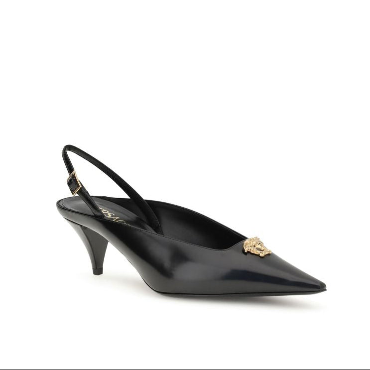 Black high-heeled shoe with a decorative gold emblem on a white background