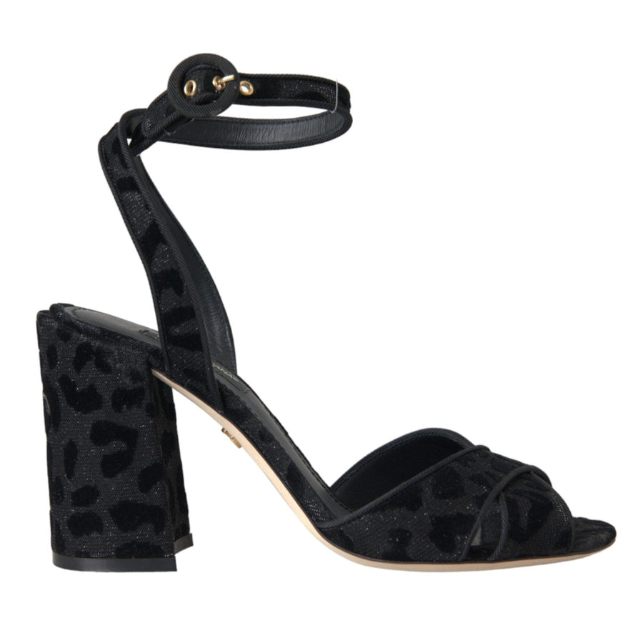 A pair of black leopard print suede ankle strap heels sandals with a leather buckle closure.