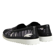 Black slip-on shoes with white soles on a white background