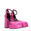 Pink high-heeled shoes with embellishments on a white background