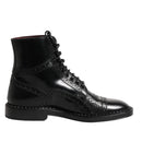 Black leather boot with decorative elements on a white background