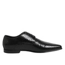 Black dress shoe with snake print pattern on a white background